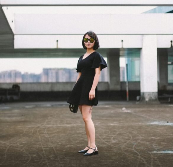 woman in black minidress woman in black minidress and black sunglasses standing on street